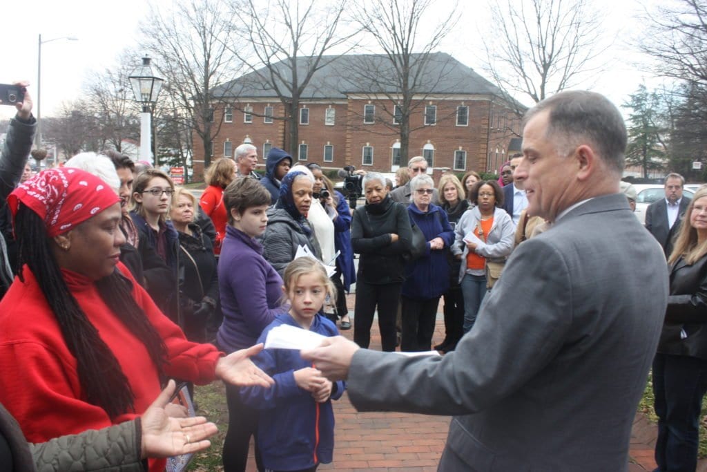 THE REV. JOHN OHMER (foreground, right) distributes programs for the dedication of the "Enslaved Persons" plaque at the historic Falls Church Saturday. (Photo: News-Press)