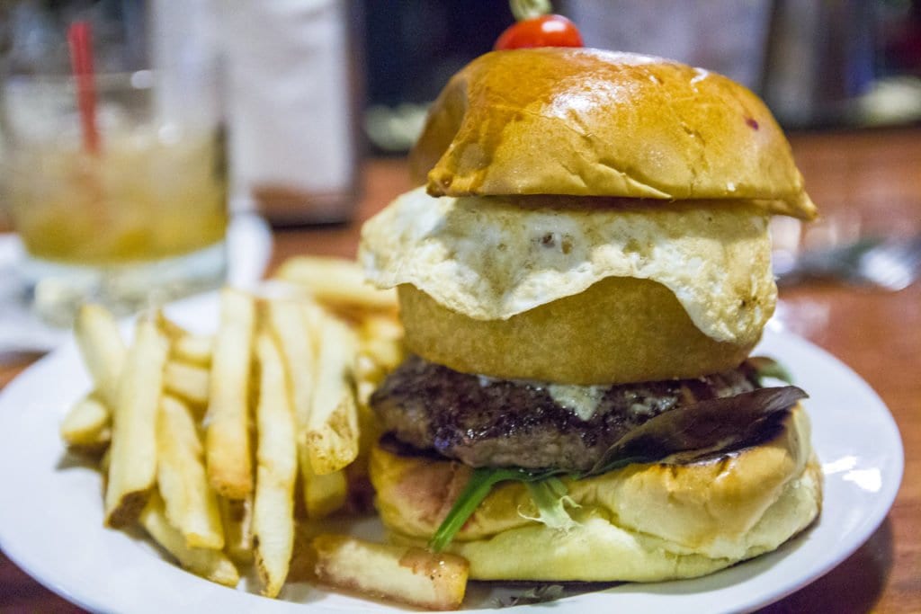 ONE OF TOWNSHEND BAR’s giant new burgers is topped with grilled onions, blue cheese, an onion ring and an over-easy egg. (Photo: Jody Fellows)
