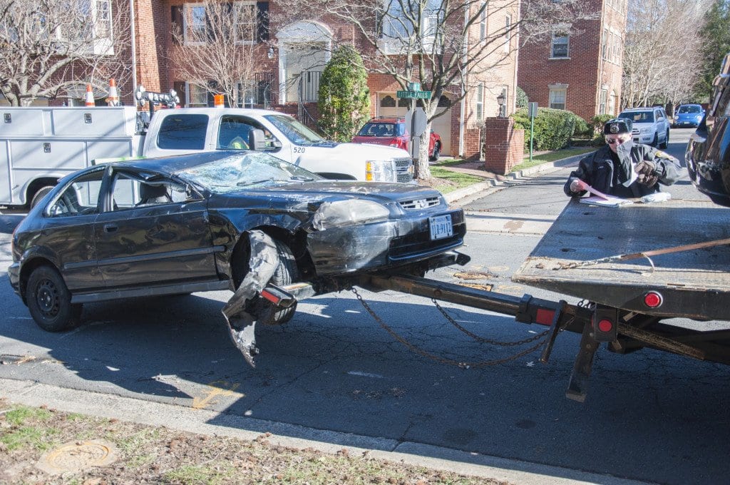 A Falls Church City police officer fills out paper work while the Honda Civic, one of the cars damaged in today's accident, is loaded onto a tow truck. (Photo: Drew Costley/News-Press)