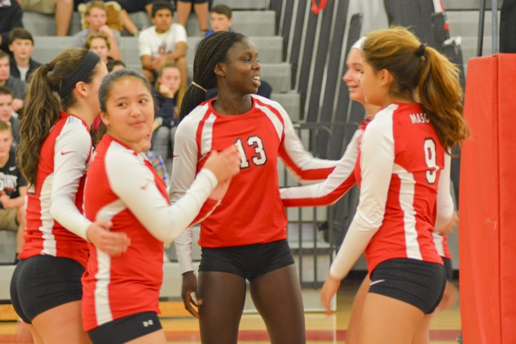 The mustangs gather around senior Vicky-Marie Addo-Ashong after scoring a point during their victory over Madison County High School on Tuesday. (Photo: Carol Sly)
