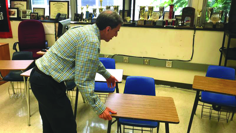 Theory of Knowledge teacher Mr. Scharff moves desks to accommodate the next class. Mr. Scharff has had to move the desks at the end of every block 3 class because of the difference in size between his classes. “One difficulty is that theory of knowledge was designed to be a seminar and having class discussions becomes difficult,” said Mr. Scharff. (Photo: Dorian Charpentier)