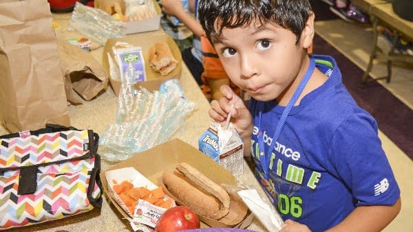 A Falls Church City Public Schools student chows down one of the menu items yesterday: a hot dog in whole wheat bun, sweet potato cubes and an apple. (Photo: Courtesy of FCCPS Photo/John Wesley Brett)