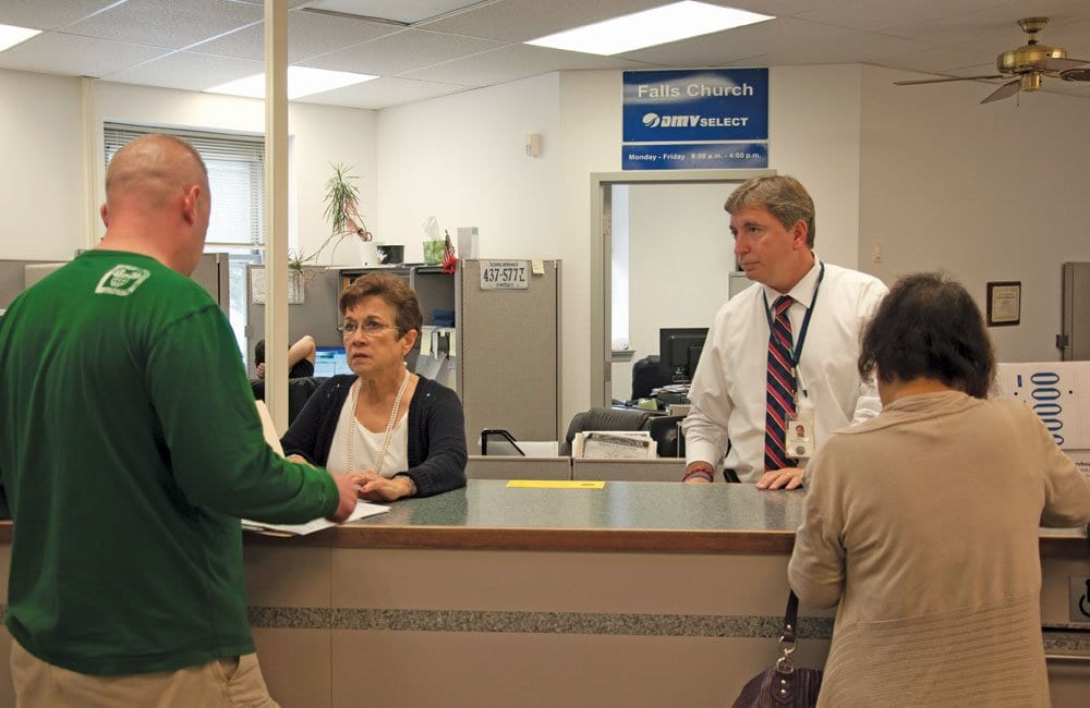 Falls Church Commissioner of the Revenue Tom Clinton (right) helps two DMV Select customers at his office in City Hall. Clinton says he plans to end the DMV Select services his office provides at the end of the month. (Photo: News-Press)