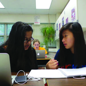 Zehara Khan (left) and Esther Kim, rising sophomores at George Mason High School, work together during George Mason’s Summer Hybrid Learning Academy, while another rising sophomore, Lucy Hoak, works in the background. Most of the students enrolled in summer school at George Mason are there taking a mandatory personal finance and economics class to free up space in their schedules during the regular academic year for electives. (Photo: Courtesy FCCPS)